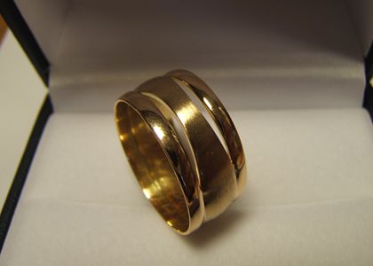 Twee gouden ringen, duidelijk herkenbaar in deze nieuwe ring, verbonden door middenstuk